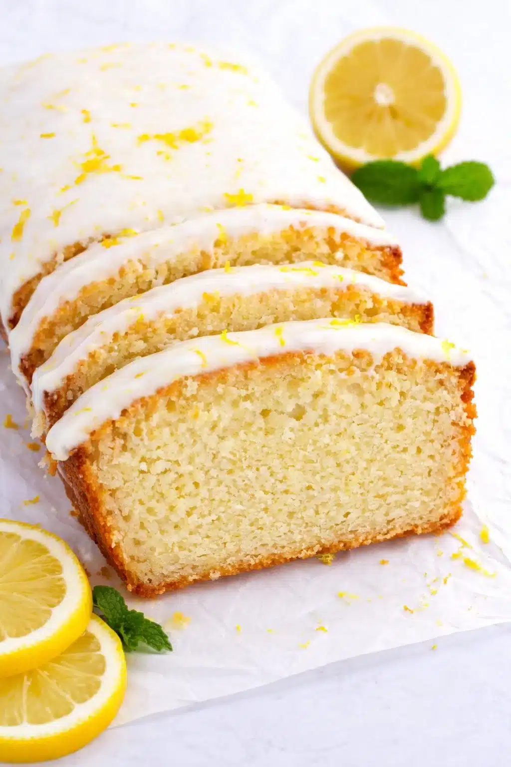 Moist Lemon Pound Cake topped with fresh lemon glaze on a rustic wooden table.